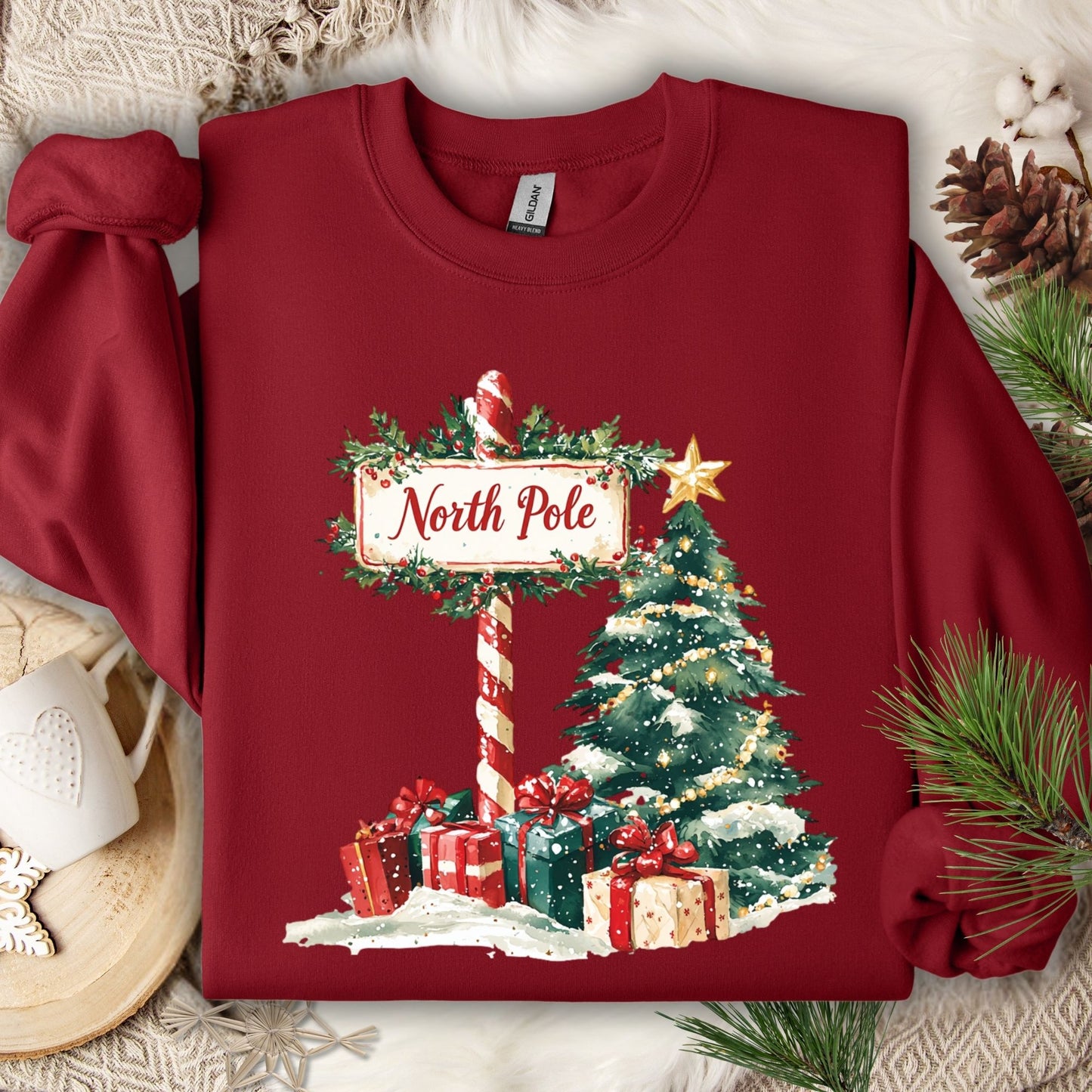 Cardinal Red Gildan sweatshirt with a watercolor North Pole sign, Christmas tree, and gifts.