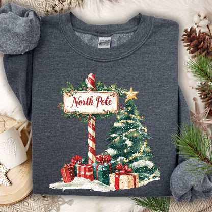 Dark Heather Gildan 18000 sweatshirt with a watercolor North Pole sign, Christmas tree, and gifts.