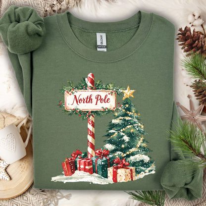Military Green Gildan 18000 sweatshirt with a watercolor North Pole sign, Christmas tree, and gifts.
