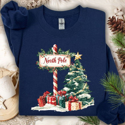 Navy Gildan sweatshirt with a watercolor North Pole sign, Christmas tree, and gifts.