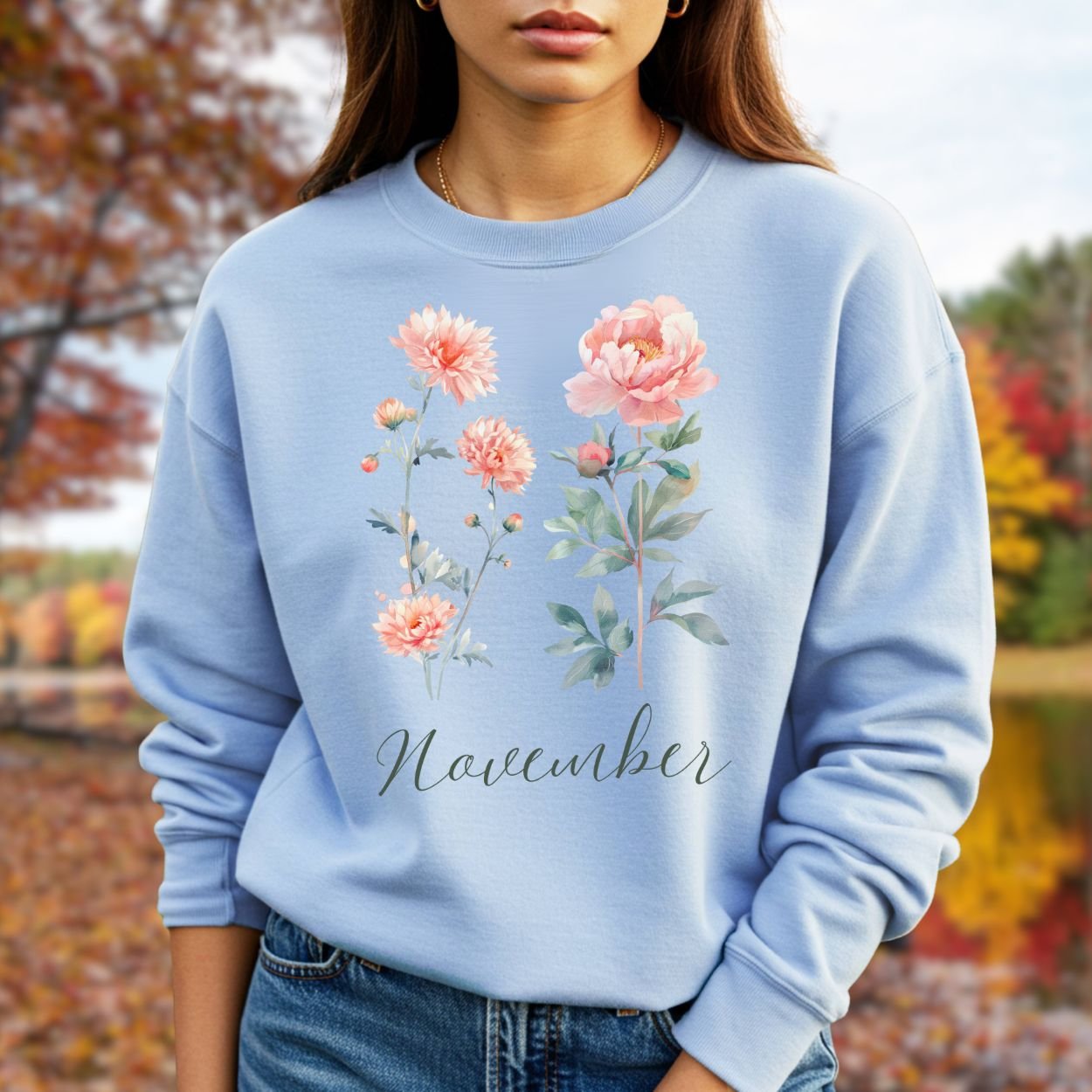 Light blue unisex sweatshirt with watercolor chrysanthemum and peony flowers, "November" text, worn outdoors.