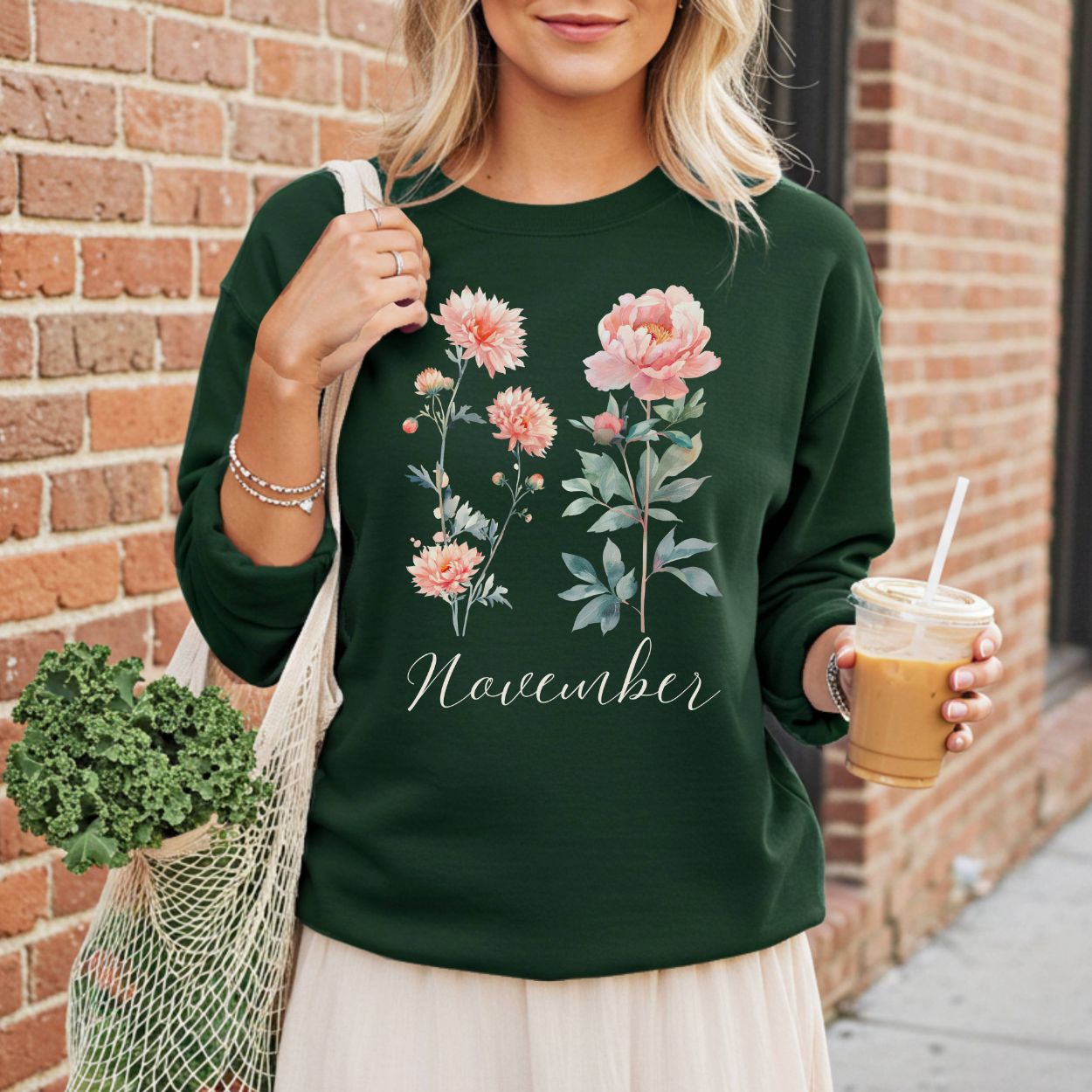 Woman in a dark green crewneck sweatshirt with watercolor chrysanthemum and peony flowers, "November" text.
