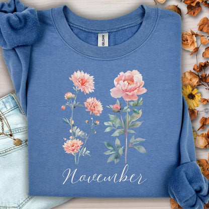 Indigo blue unisex sweatshirt with watercolor chrysanthemum and peony, "November" text, and ribbed cuffs.