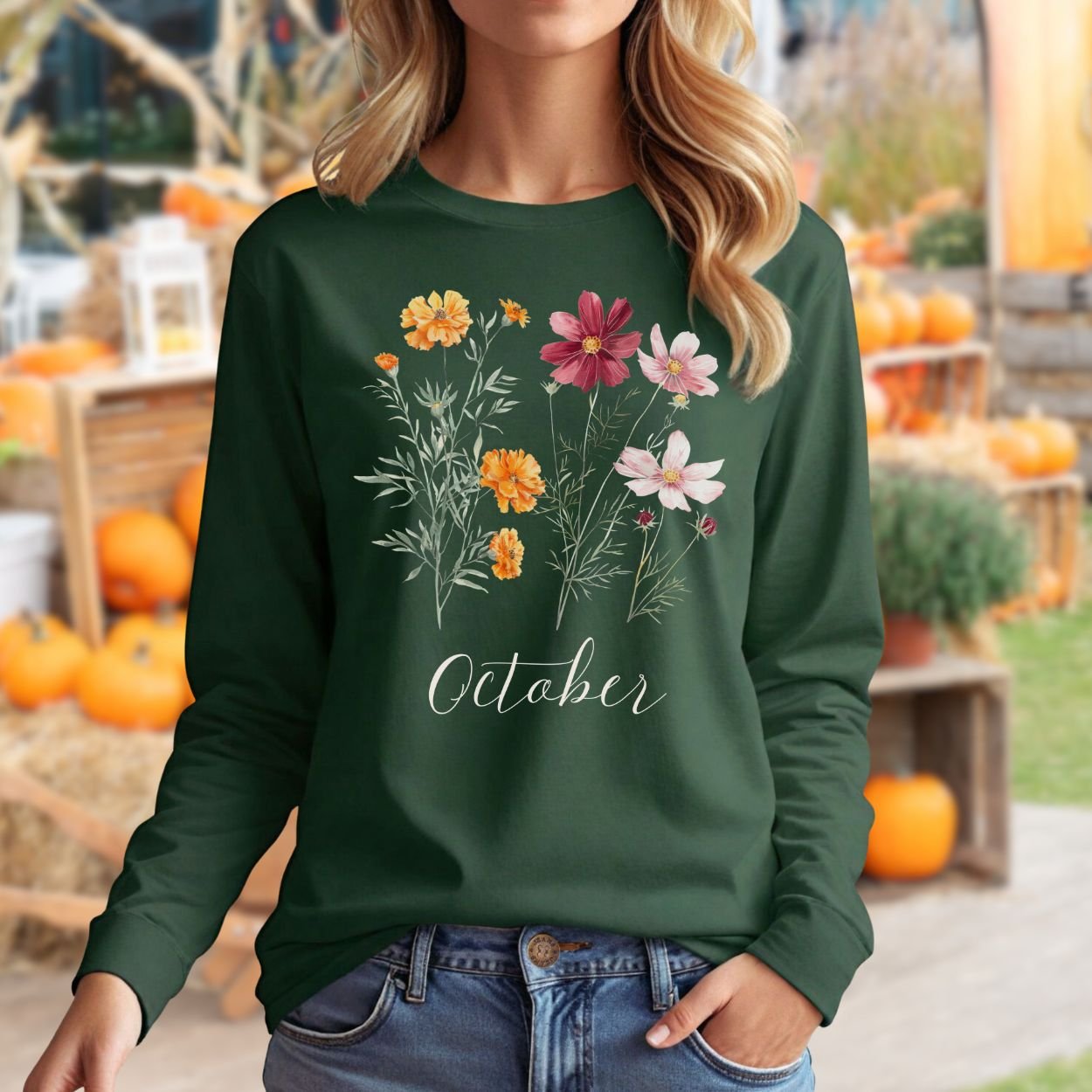 Woman in a dark green long sleeve tee with watercolor marigold and cosmos flowers and "October" text.