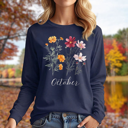 Navy long sleeve tee with watercolor marigold and cosmos flowers, "October" script, worn by a woman outdoors.