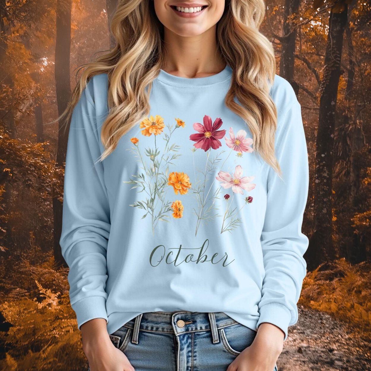 Light blue long sleeve tee with watercolor marigold and cosmos flowers, "October" script, worn by a woman.