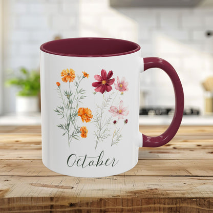 White 11oz ceramic mug with maroon handle and interior, featuring watercolor cosmos and marigold blooms and "October.