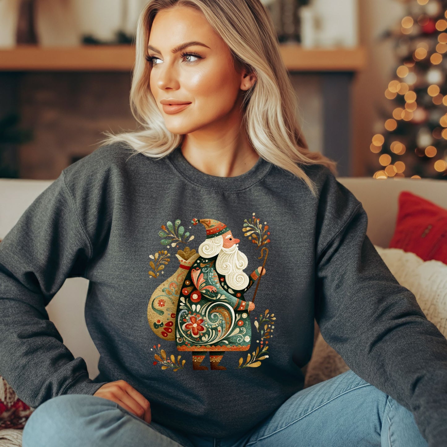 Woman in a dark gray sweatshirt with a colorful folk art St. Nicholas design, sitting on a couch.