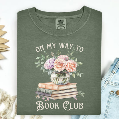 Moss green "On My Way To Book Club" t-shirt with watercolor vintage books and floral vase design.