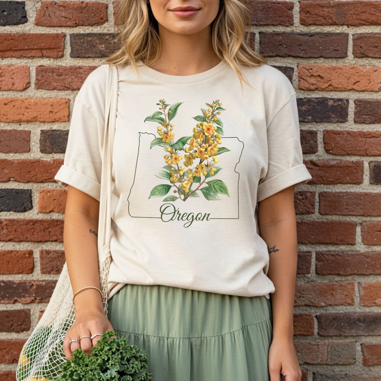 Woman in a relaxed-fit, garment-dyed tee with an Oregon grape blossom design inside a state outline.