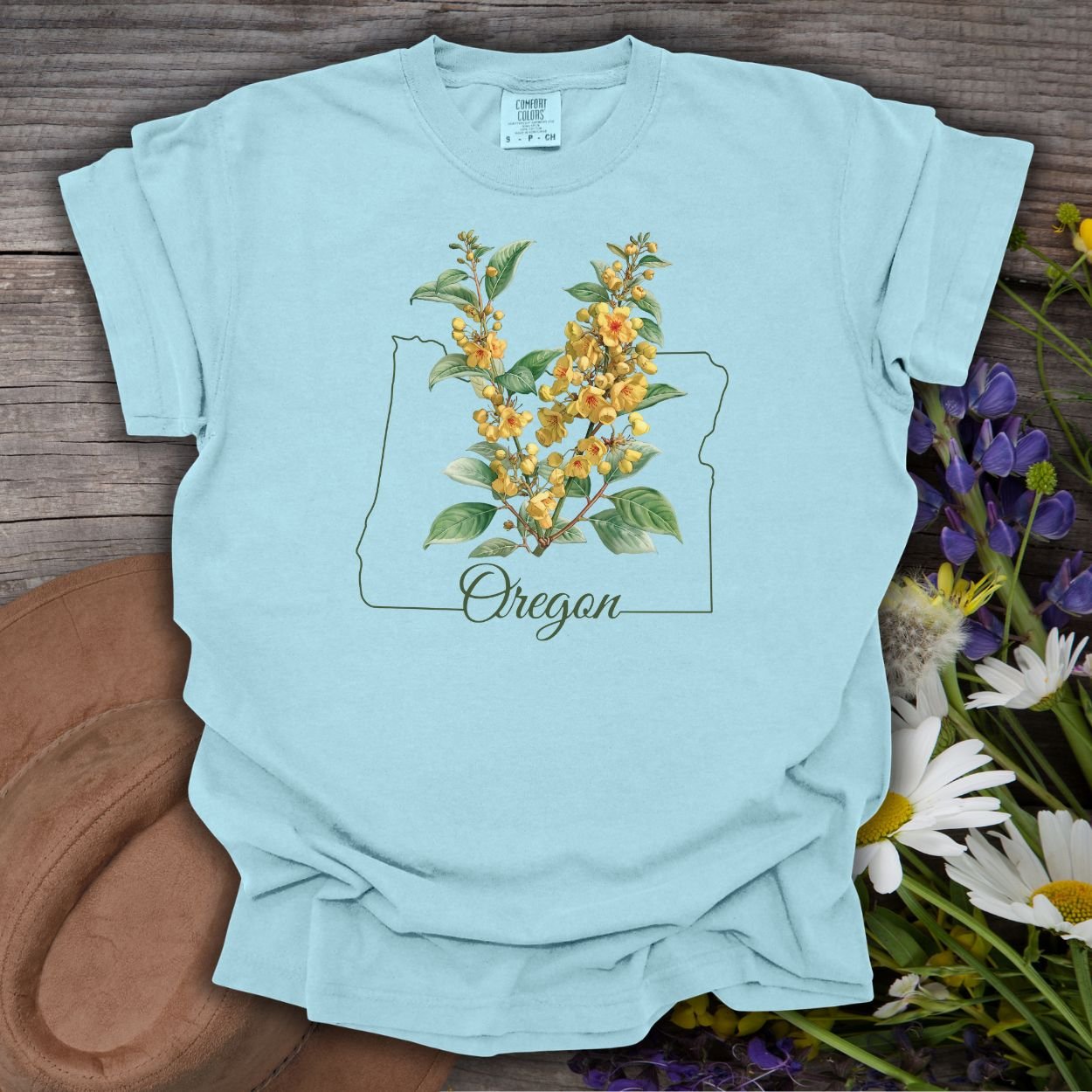 Chambray blue garment-dyed cotton tee with a hand-drawn Oregon outline and warm yellow Oregon Grape blossoms.