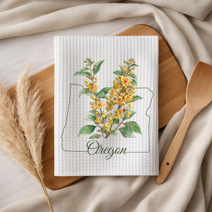 White waffle-weave microfiber tea towel with a yellow Oregon grape blossom print inside the Oregon state outline.