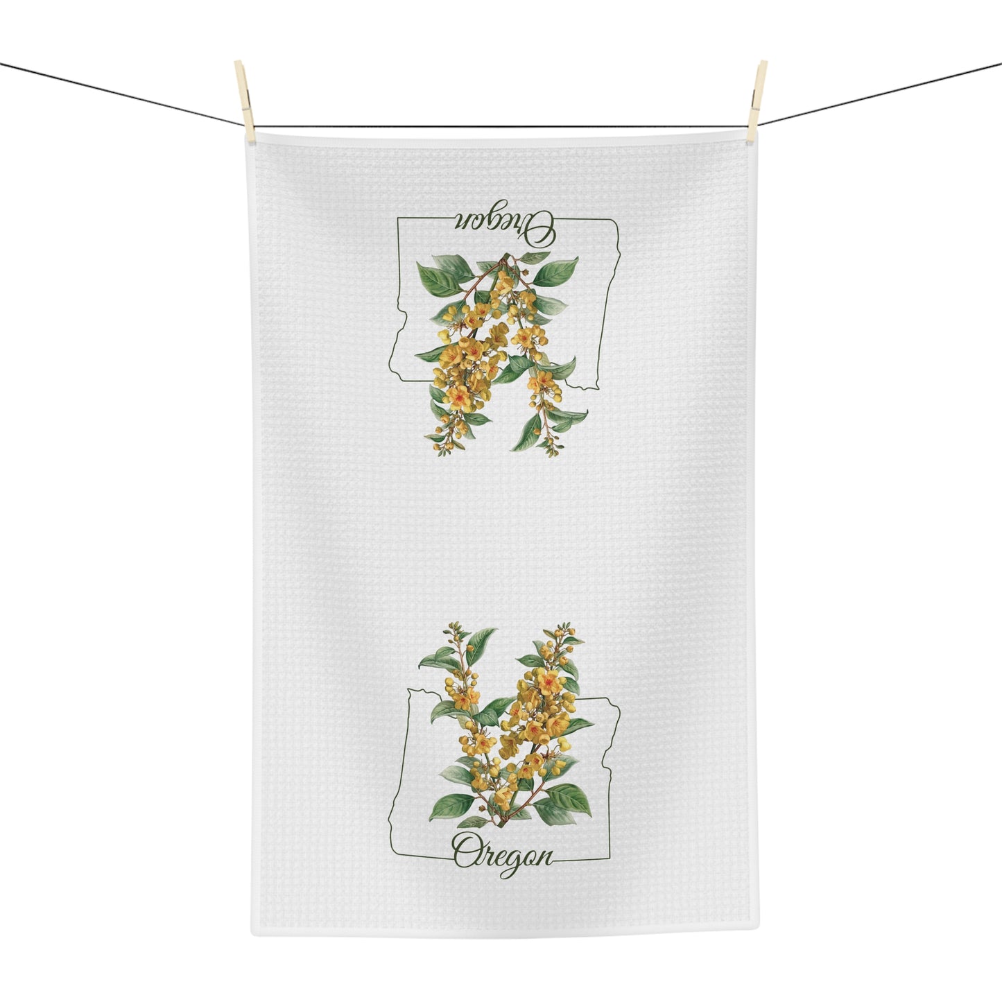 White microfiber tea towel with Oregon Grape Blossom print and state outline, hanging on a line.