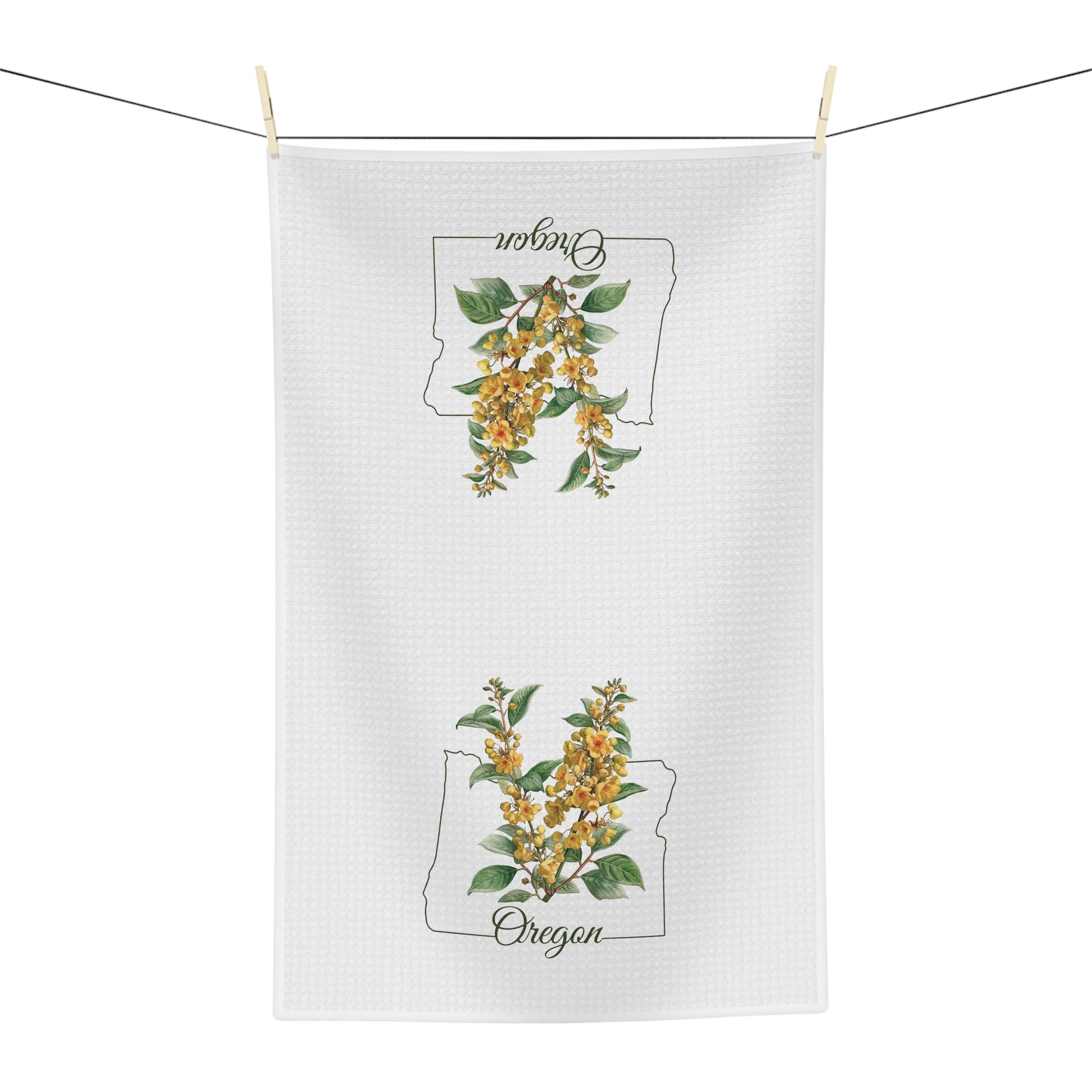 White microfiber tea towel with Oregon Grape Blossom print and state outline, hanging on a line.