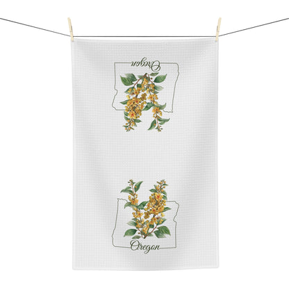 White microfiber tea towel with Oregon Grape Blossom print and state outline, hanging on a line.