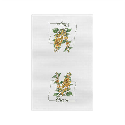 White microfiber tea towel with two Oregon state outlines framing golden Oregon Grape blossoms.
