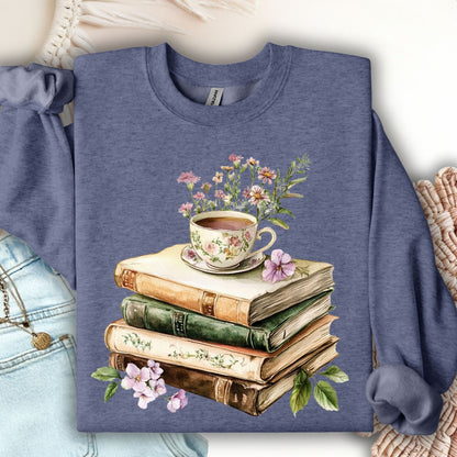 Heathered blue crewneck sweatshirt with a vintage illustration of stacked books, a floral teacup, and greenery.