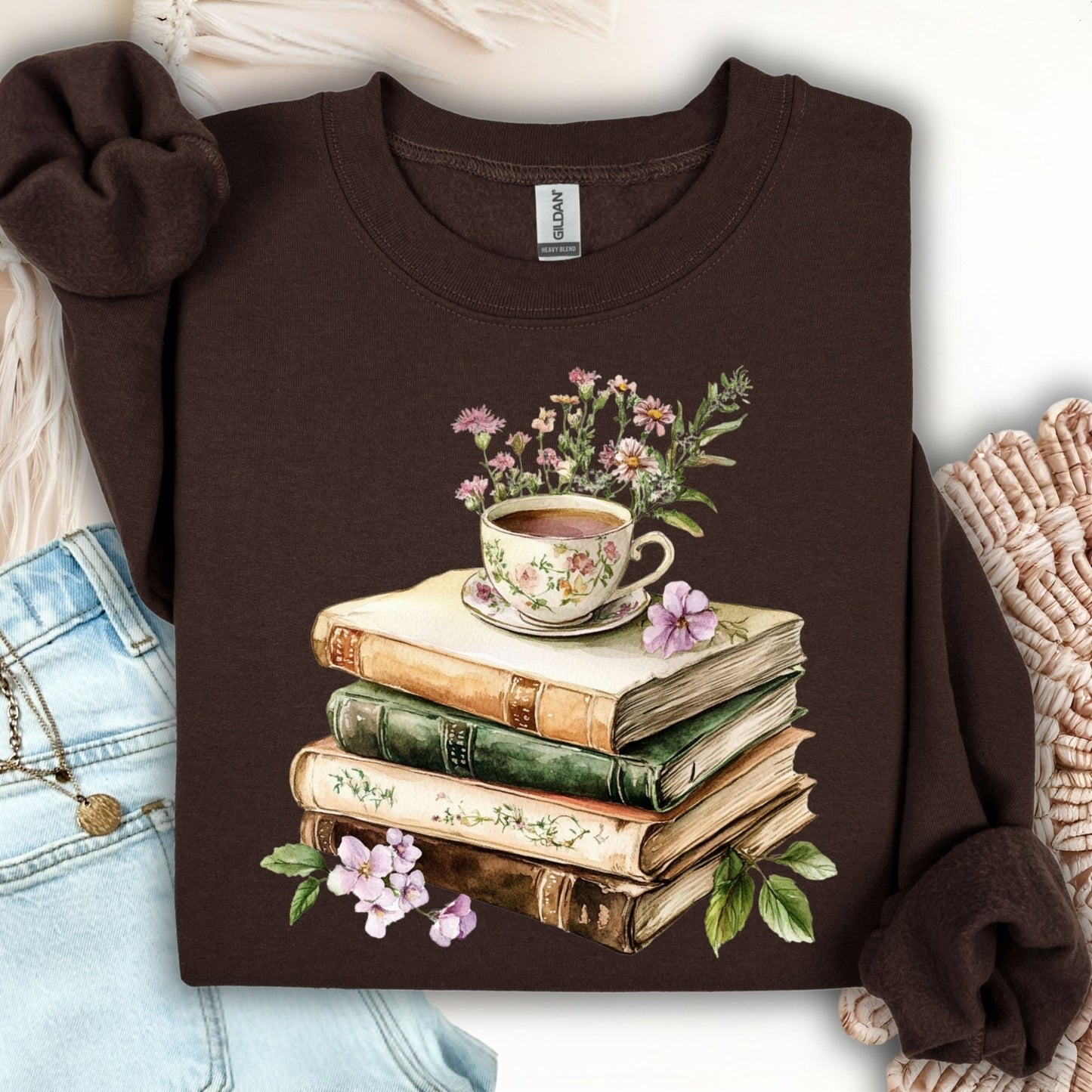 Dark chocolate crewneck sweatshirt with a vintage illustration of stacked books, a floral teacup, and greenery.