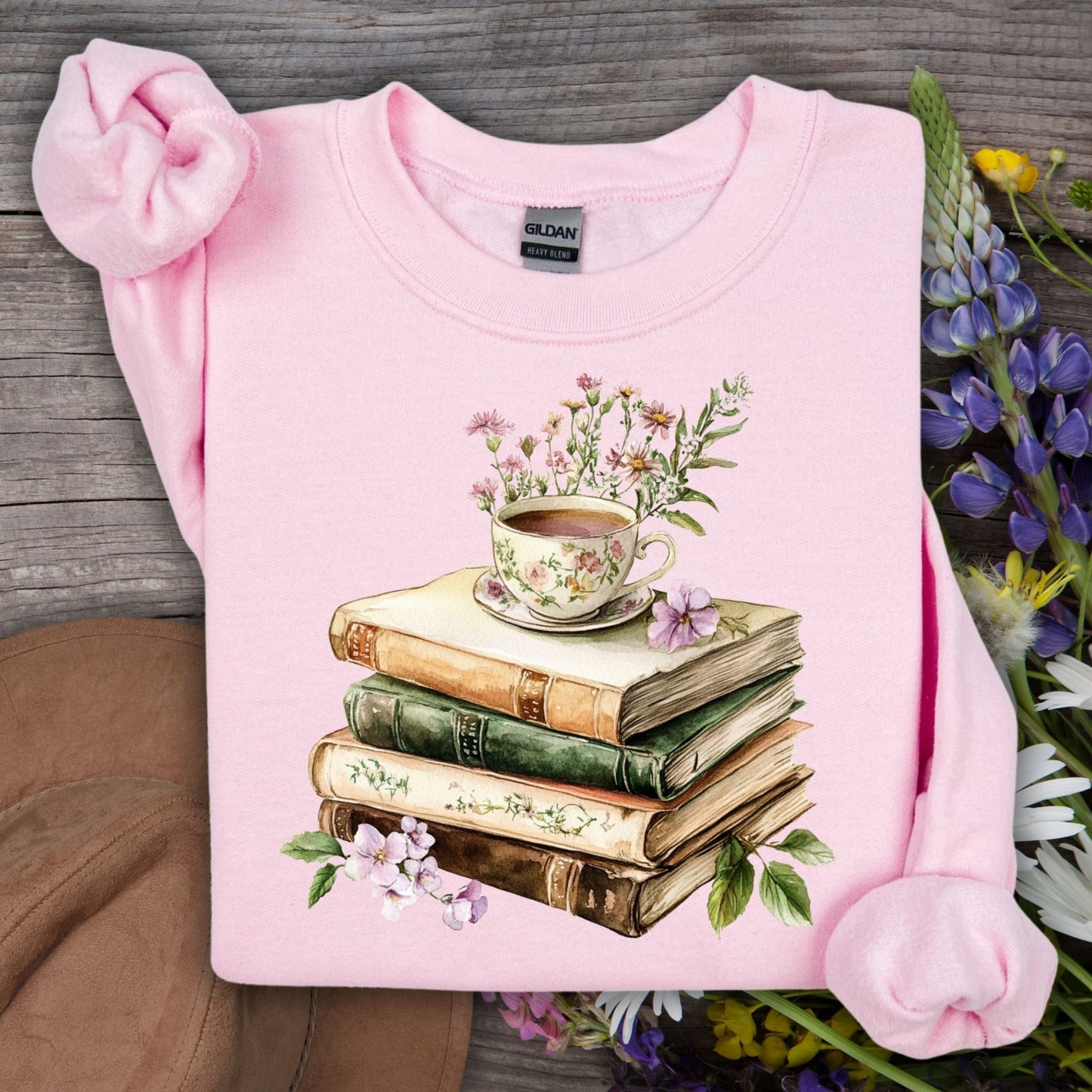 Light pink Gildan sweatshirt with a vintage illustration of stacked books, a floral teacup, and greenery.