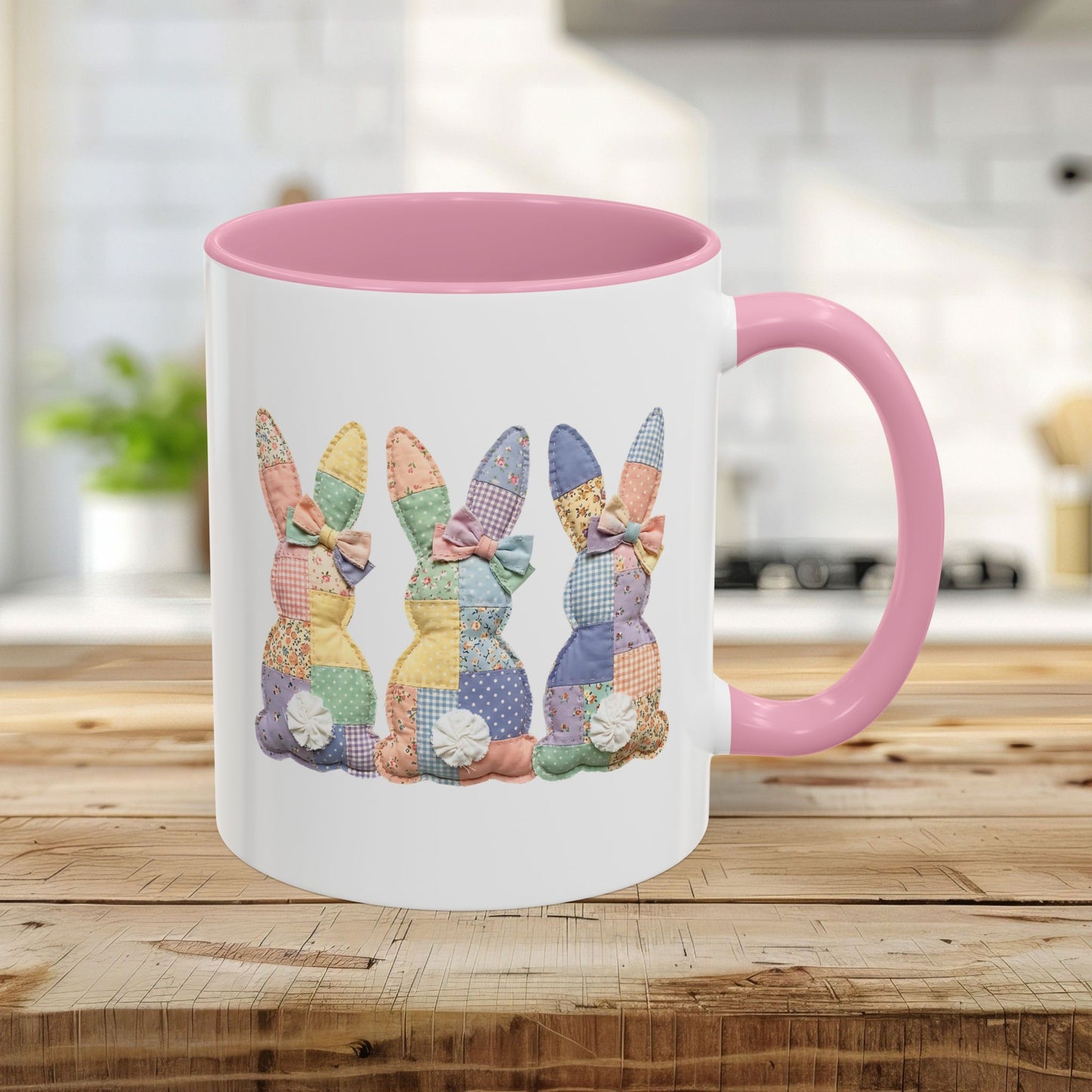 11oz white ceramic mug with pink handle and interior, featuring three pastel patchwork bunnies.
