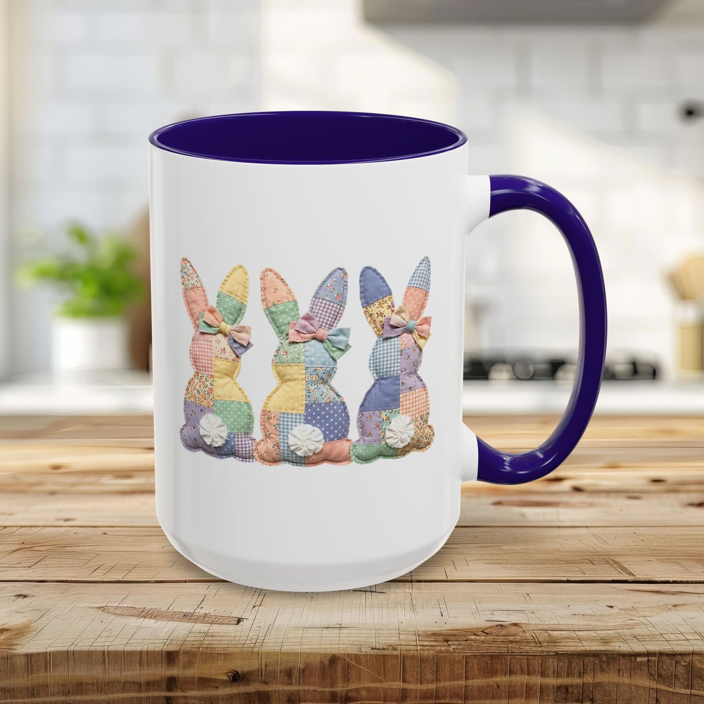 White 15oz ceramic mug with blue interior/handle, featuring three pastel patchwork bunnies.
