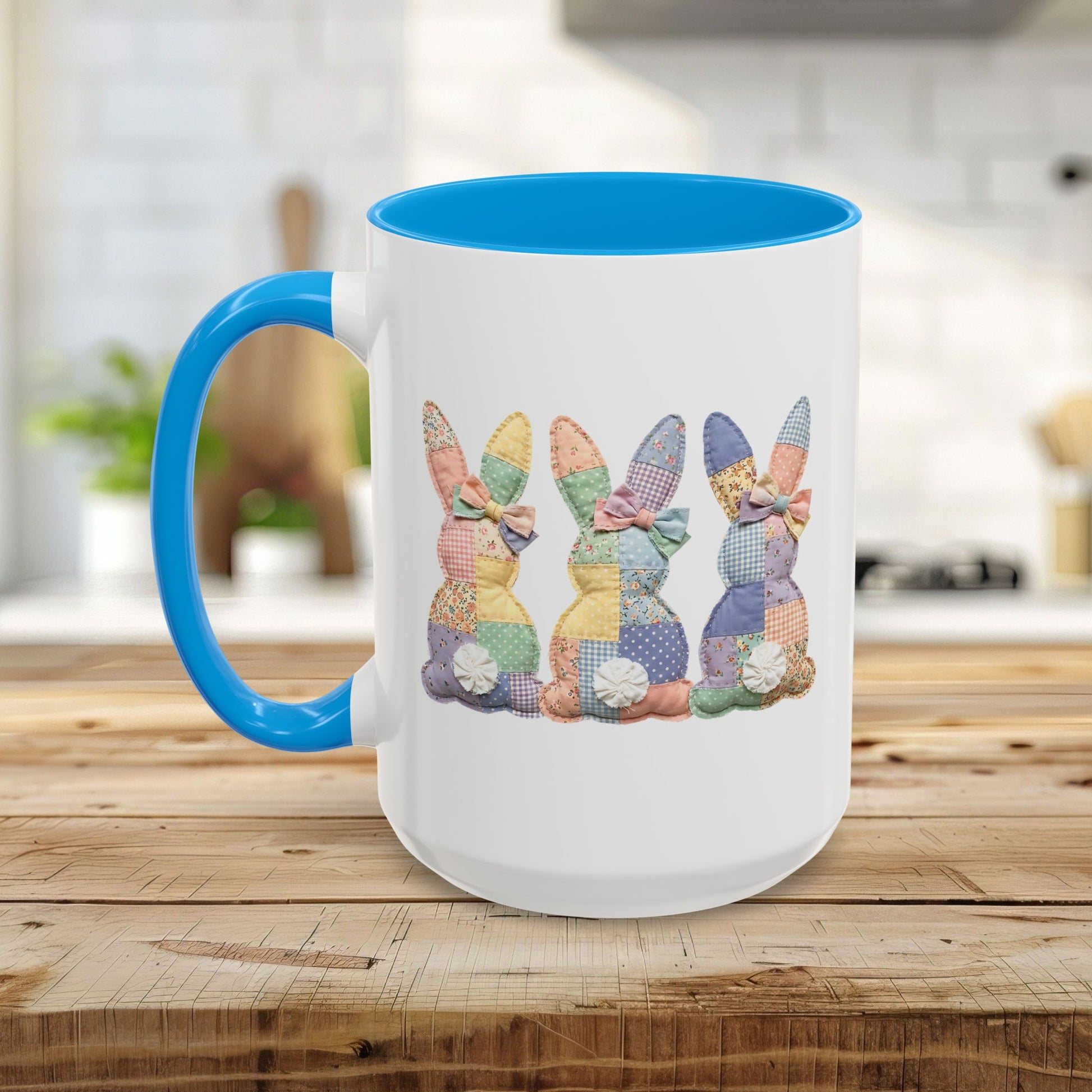 White ceramic mug with blue handle and interior, featuring three pastel patchwork bunnies.