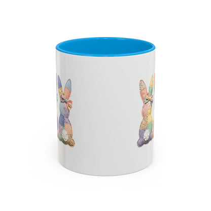 White ceramic mug with a blue interior and handle, featuring pastel patchwork bunny designs.