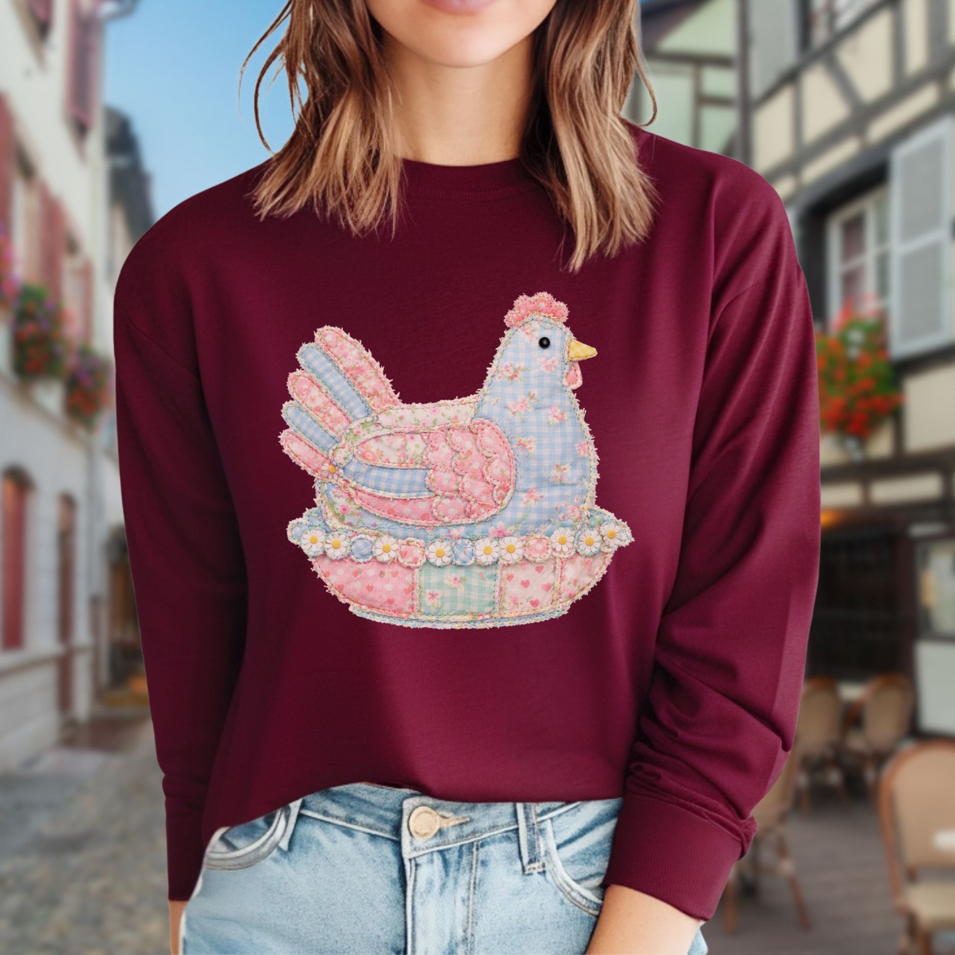 Maroon long-sleeve tee with a pastel faux patchwork hen in a nest of flowers.
