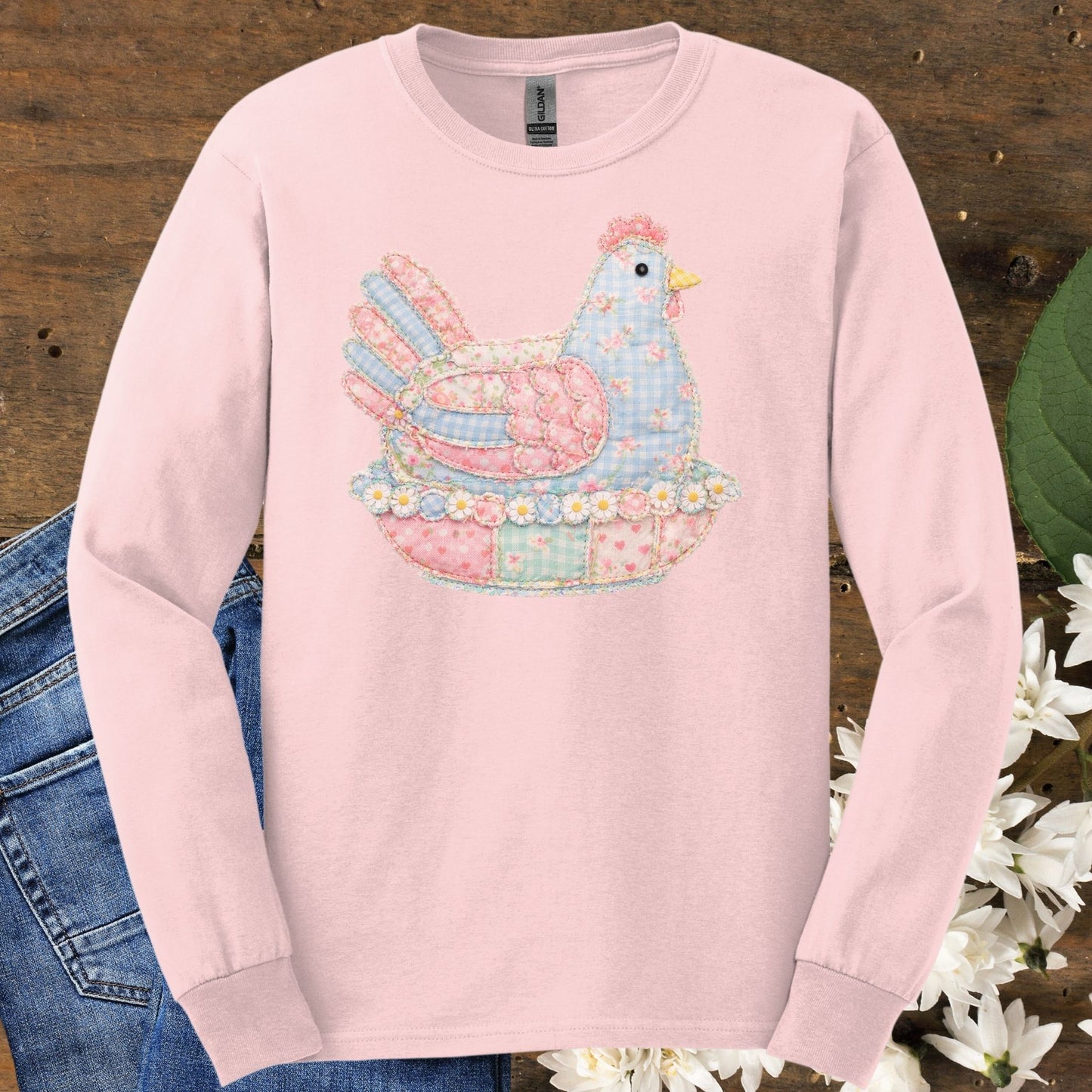 Light pink long sleeve tee with a pastel faux patchwork hen in a nest of flowers.