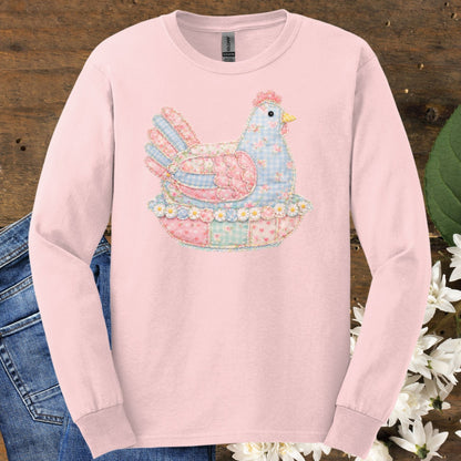 Light pink long sleeve tee with a pastel faux patchwork hen in a nest of flowers.