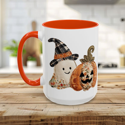 White ceramic mug with orange handle and interior, featuring a patchwork ghost in a plaid witch hat and a floral jack o'lantern.