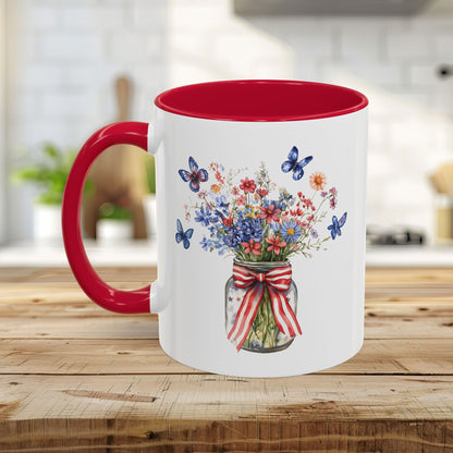 White ceramic mug with red interior and handle, featuring a watercolor mason jar bouquet with patriotic flowers and blue butterflies.