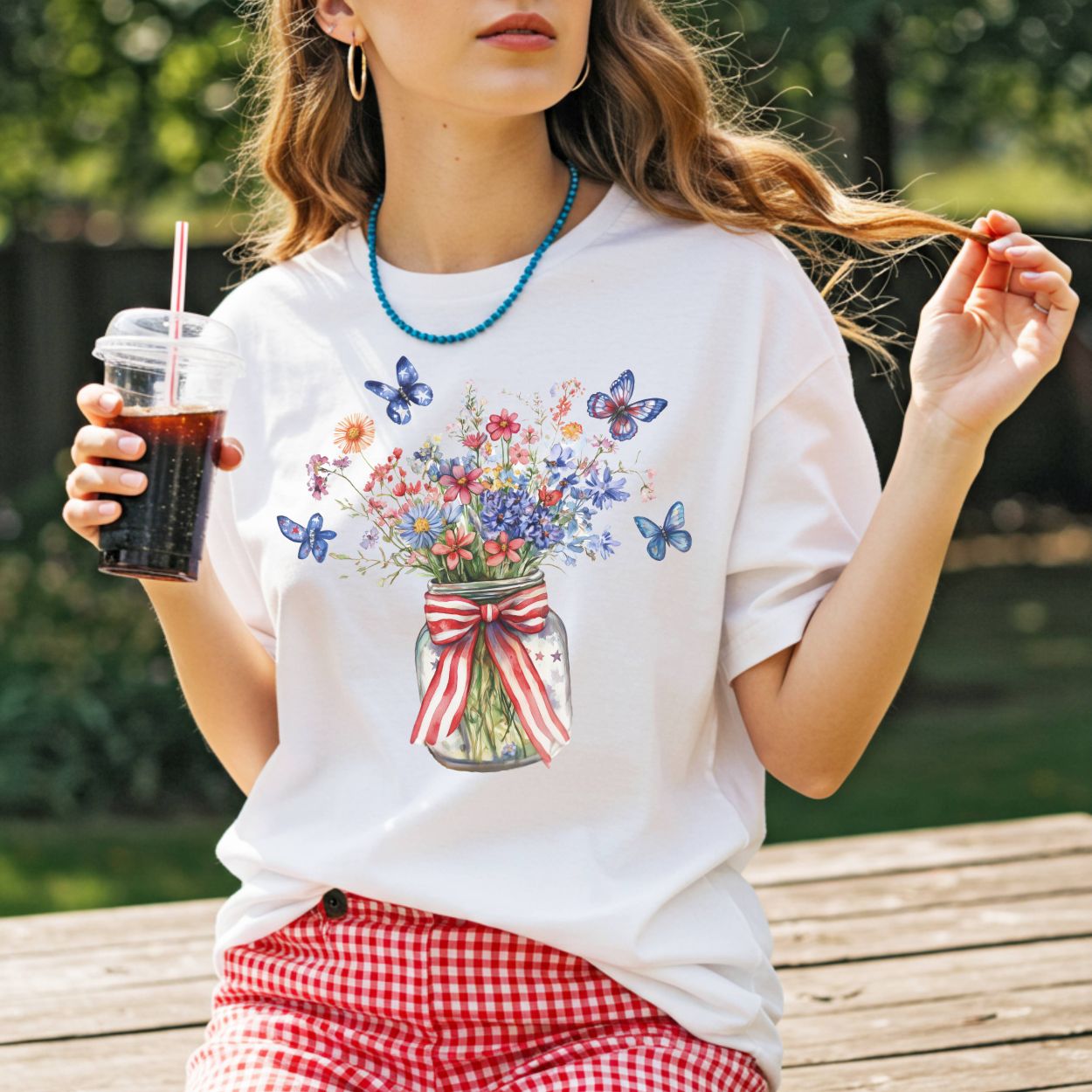 White t-shirt with a watercolor mason jar of wildflowers, patriotic ribbon, and blue butterflies.
