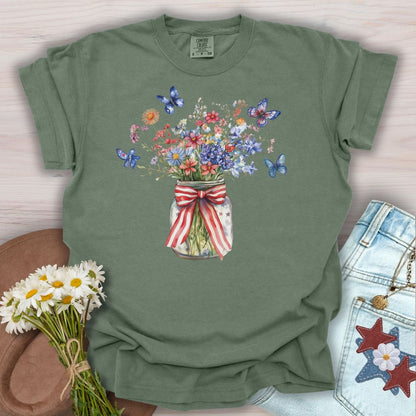 Moss S t-shirt with a watercolor mason jar of wildflowers, patriotic ribbon, and blue butterflies.