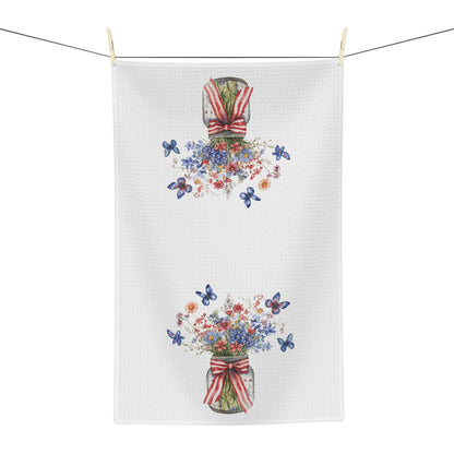 White microfiber tea towel with watercolor patriotic floral bouquets in mason jars and blue butterflies.