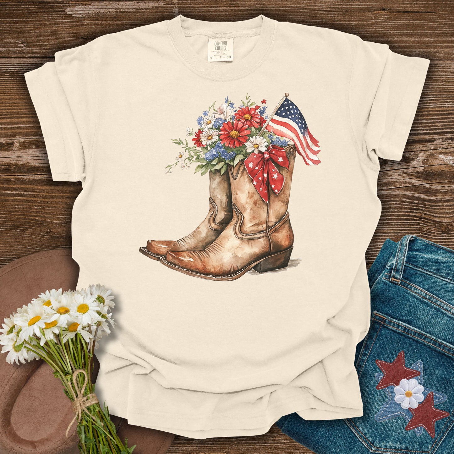 Ivory S t-shirt with watercolor cowboy boots, floral bouquet, and American flag design.