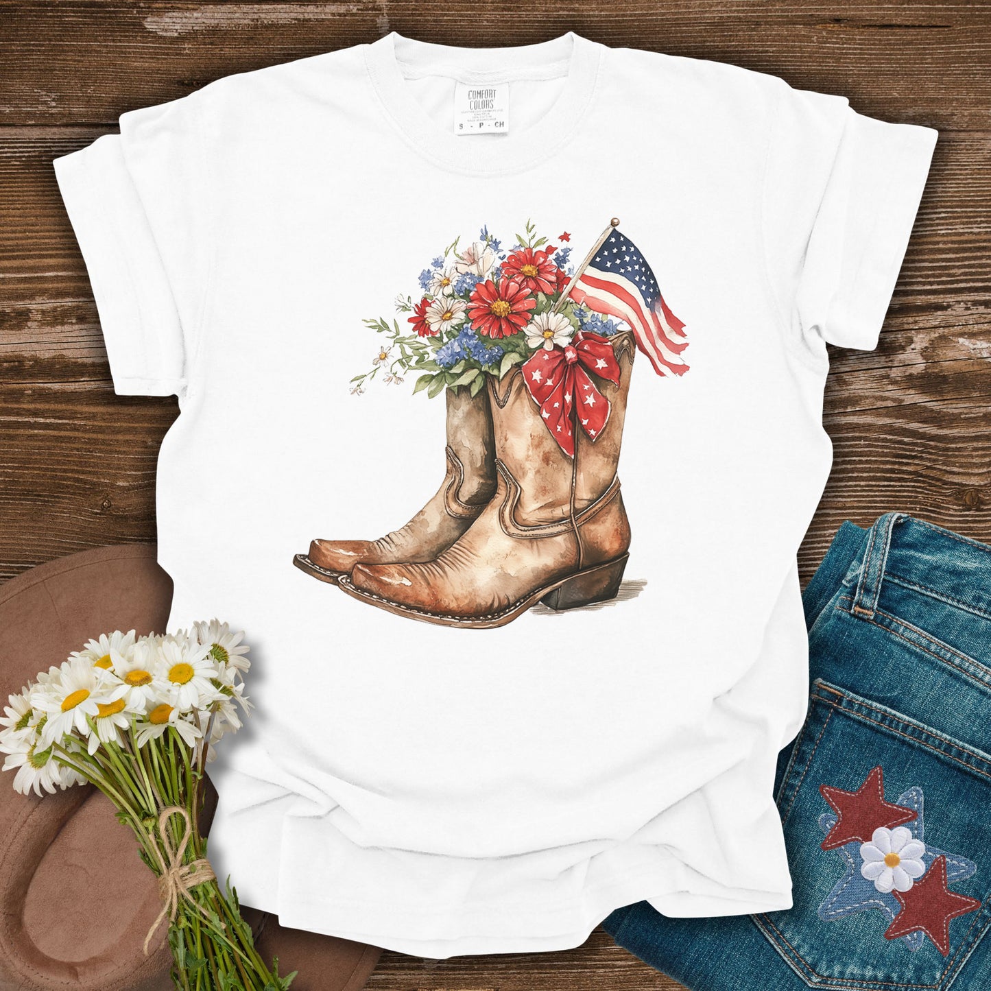 White t-shirt with watercolor cowboy boots, floral arrangement, and American flag.