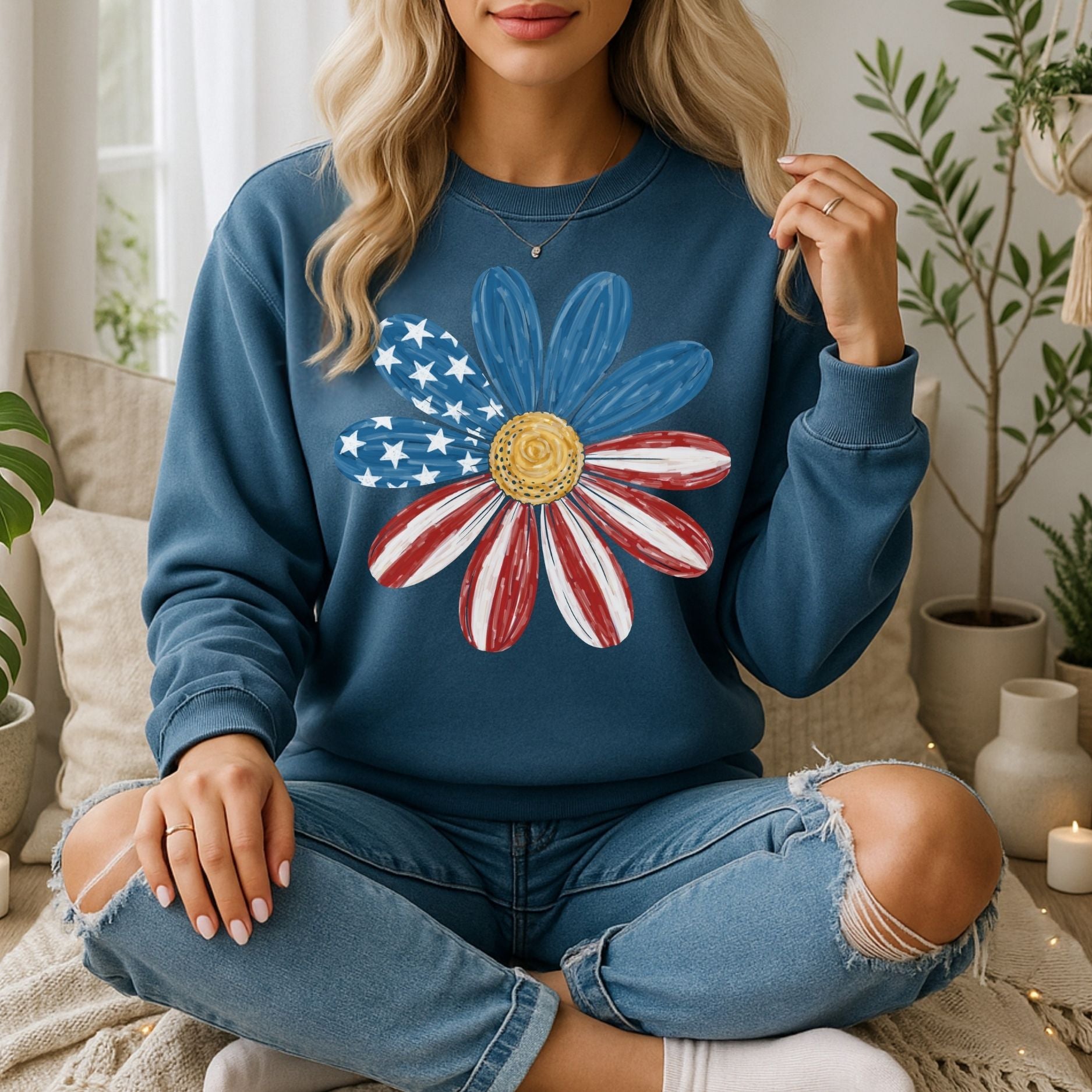 Woman in a blue crewneck sweatshirt with a hand-painted American flag daisy design, ripped jeans, and white socks.