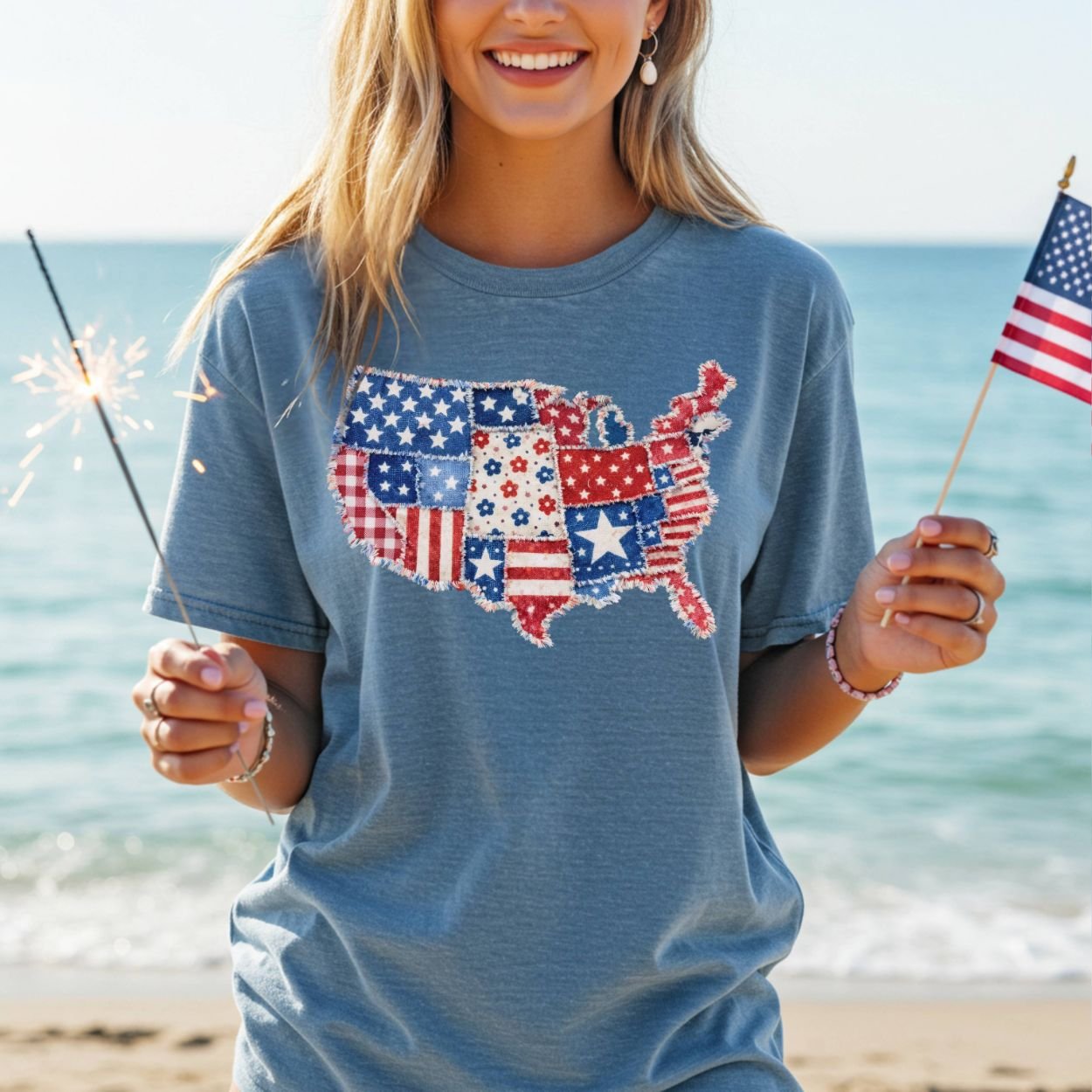 Woman in a blue t-shirt with a printed patriotic patchwork USA map, holding a sparkler and American flag.