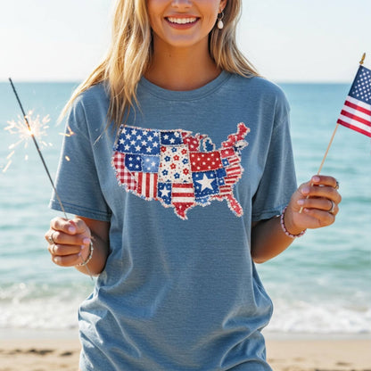 Woman in a blue t-shirt with a printed patriotic patchwork USA map, holding a sparkler and American flag.