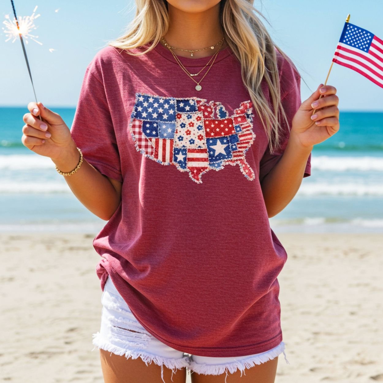 Woman in a relaxed-fit, garment-dyed red t-shirt with a printed faux patchwork USA map, holding a sparkler and flag.