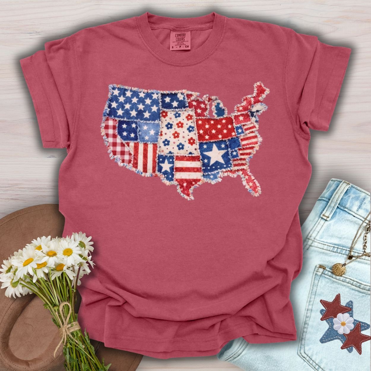 Crimson S t-shirt with a printed faux patchwork map of America, featuring stars, stripes, and floral patterns.