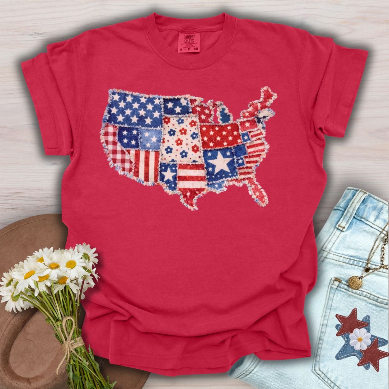 Red S-size t-shirt with a printed faux patchwork map of America, featuring stars, stripes, and floral patterns.