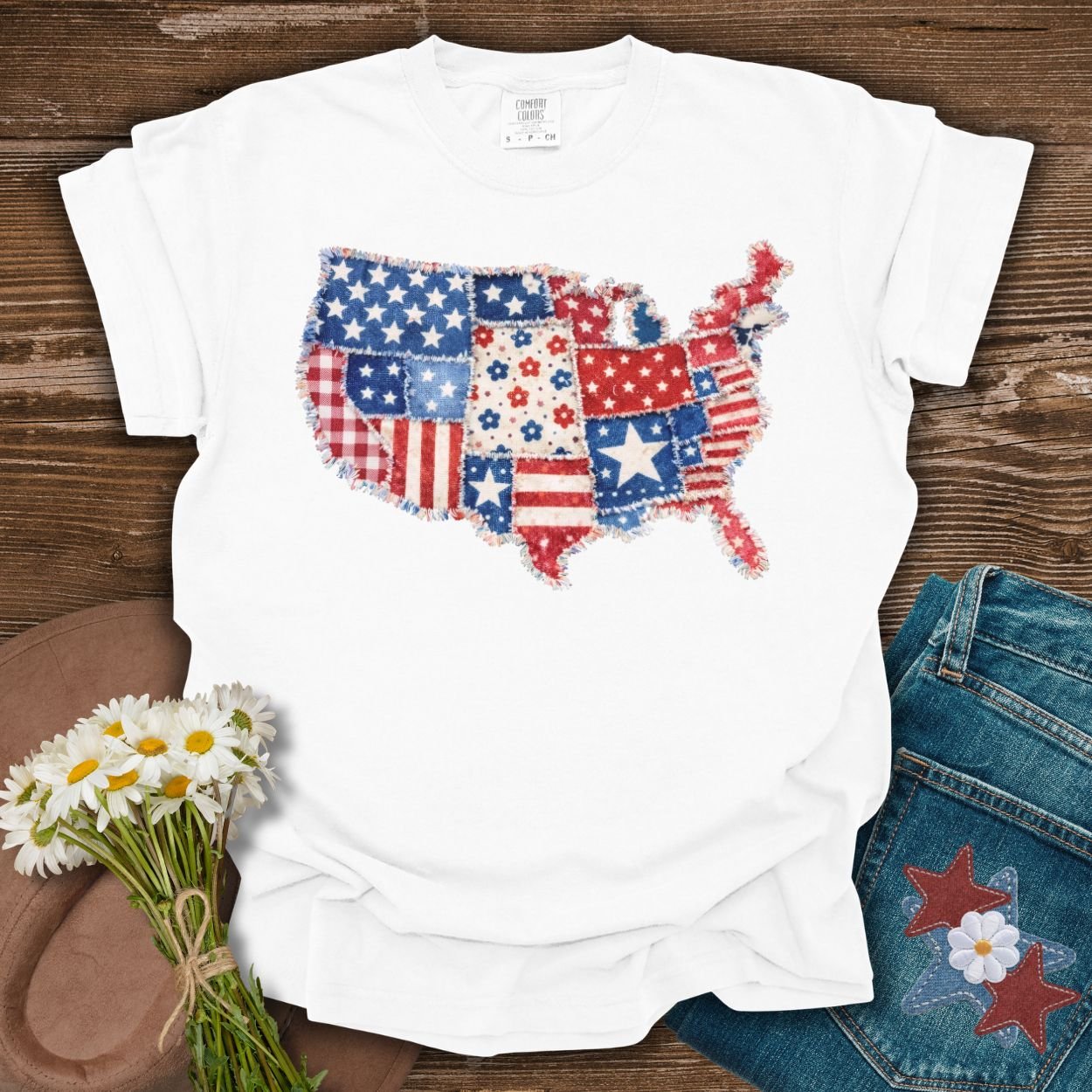 White S t-shirt with a printed faux patchwork US map in patriotic red, white, and blue patterns.