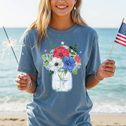 Garment-dyed blue t-shirt with a watercolor patriotic floral bouquet in a mason jar design, featuring red, white, and blue anemones and stars.