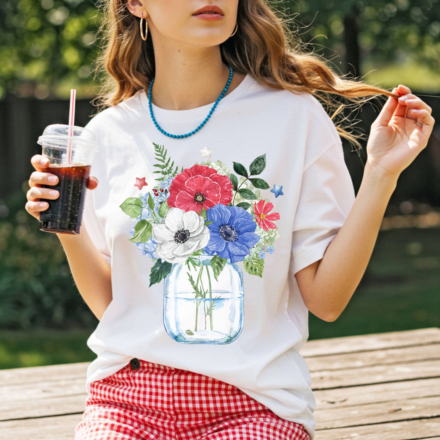 White t-shirt with a watercolor patriotic floral bouquet in a mason jar, featuring red, white, and blue anemones and stars.