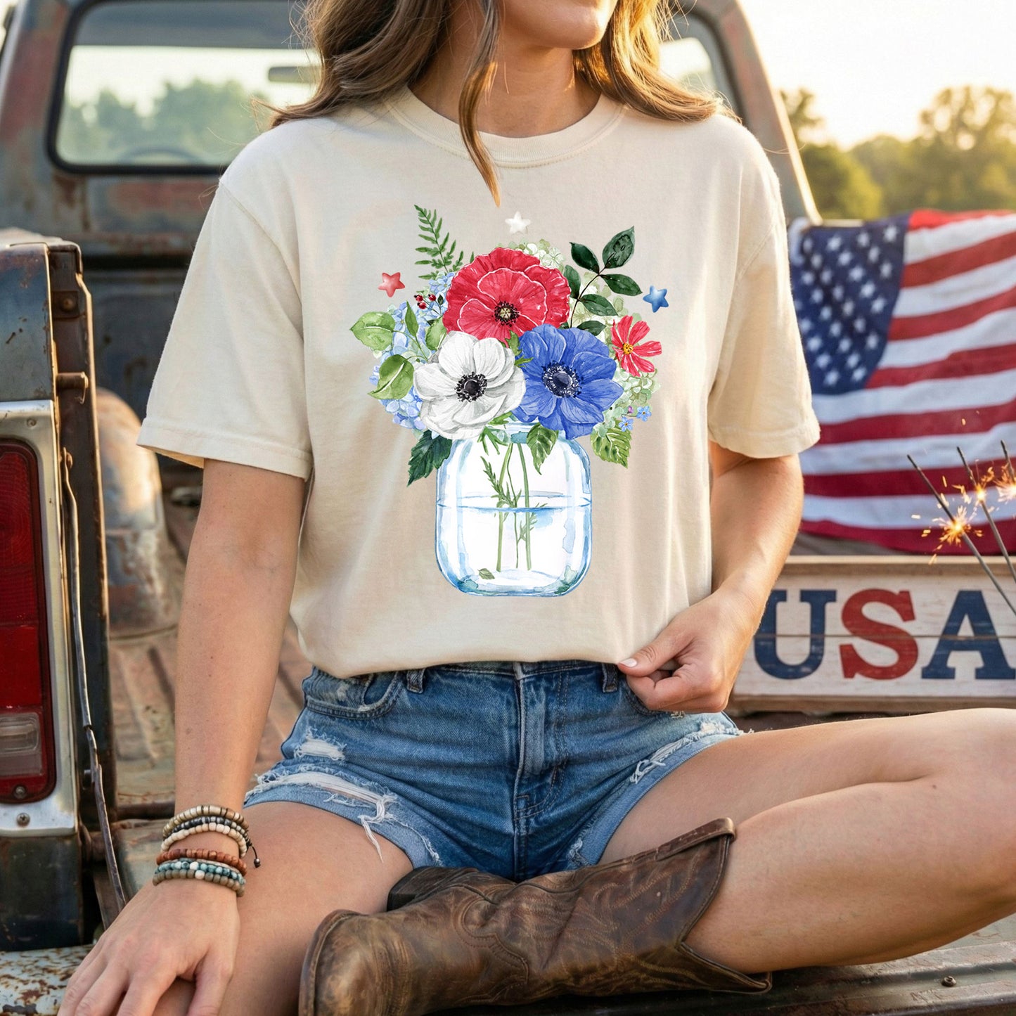 Patriotic floral bouquet in a mason jar with red, white, and blue flowers, stars, and greenery on a beige t-shirt.