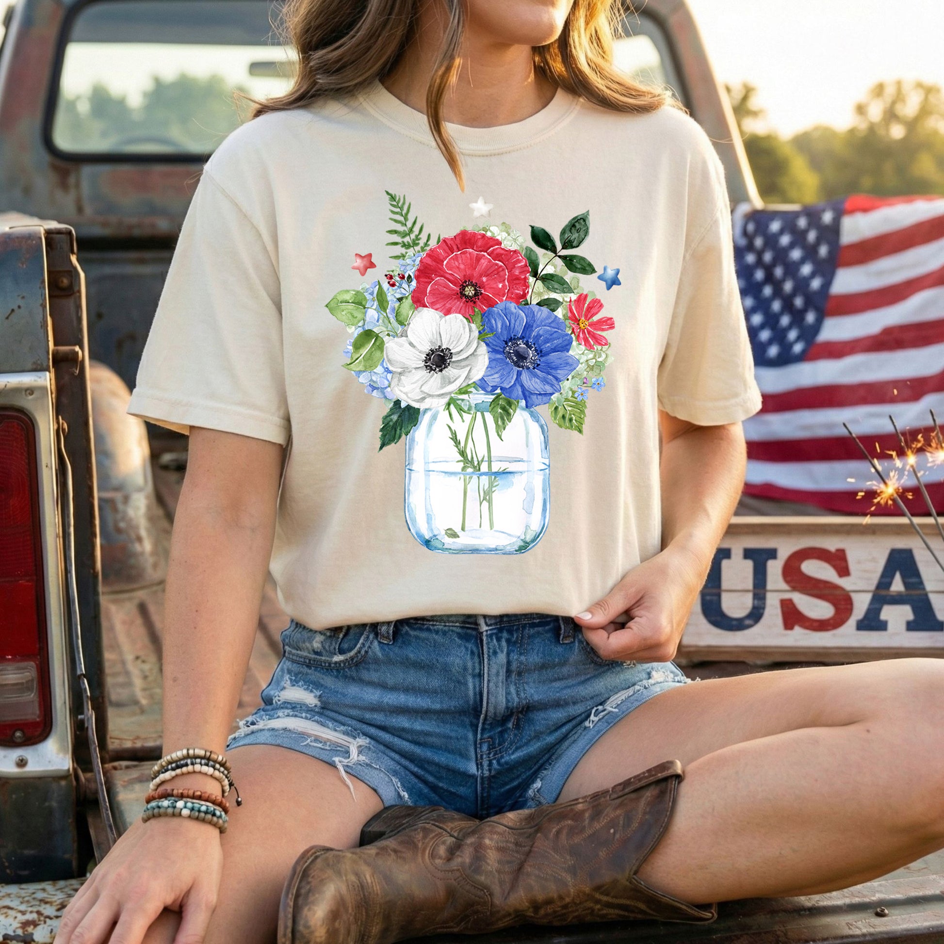 Patriotic floral bouquet in a mason jar with red, white, and blue flowers, stars, and greenery on a beige t-shirt.