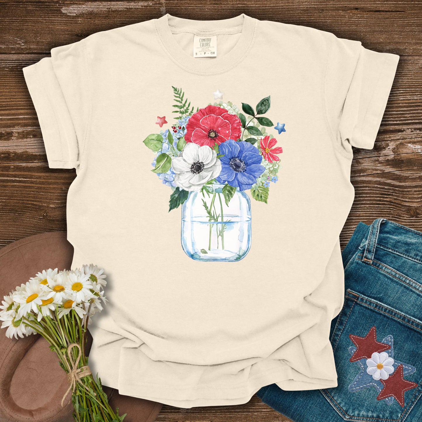 Ivory S t-shirt with a watercolor patriotic floral bouquet in a mason jar, featuring red, white, and blue anemones and stars.