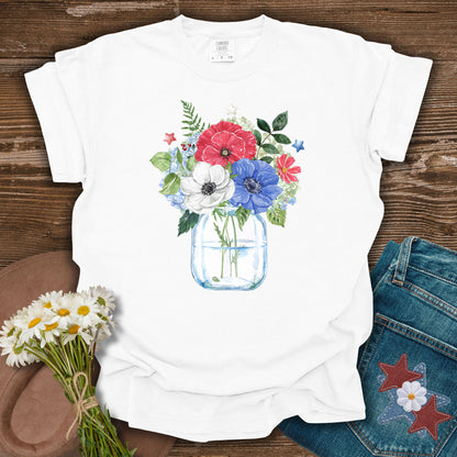White S t-shirt with a watercolor patriotic floral bouquet in a mason jar, featuring red, white, and blue anemones and stars.